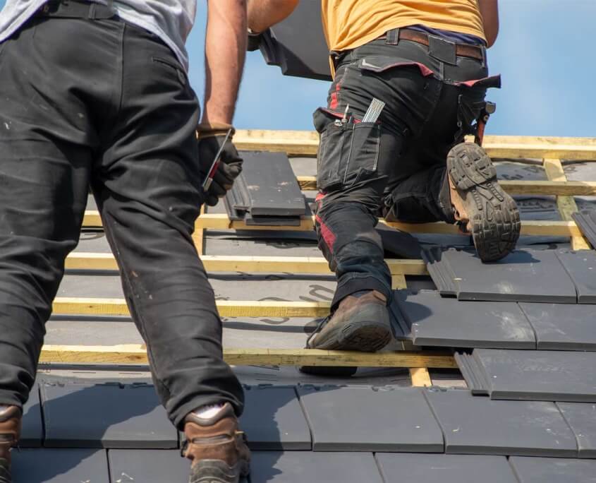 Close up of men applying roof shingles to residential roof