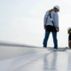 two roofers performing routine inspection on top of roof